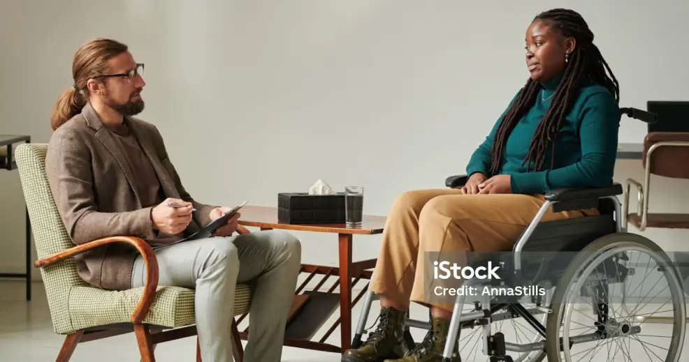 Two people talking, one using a wheelchair