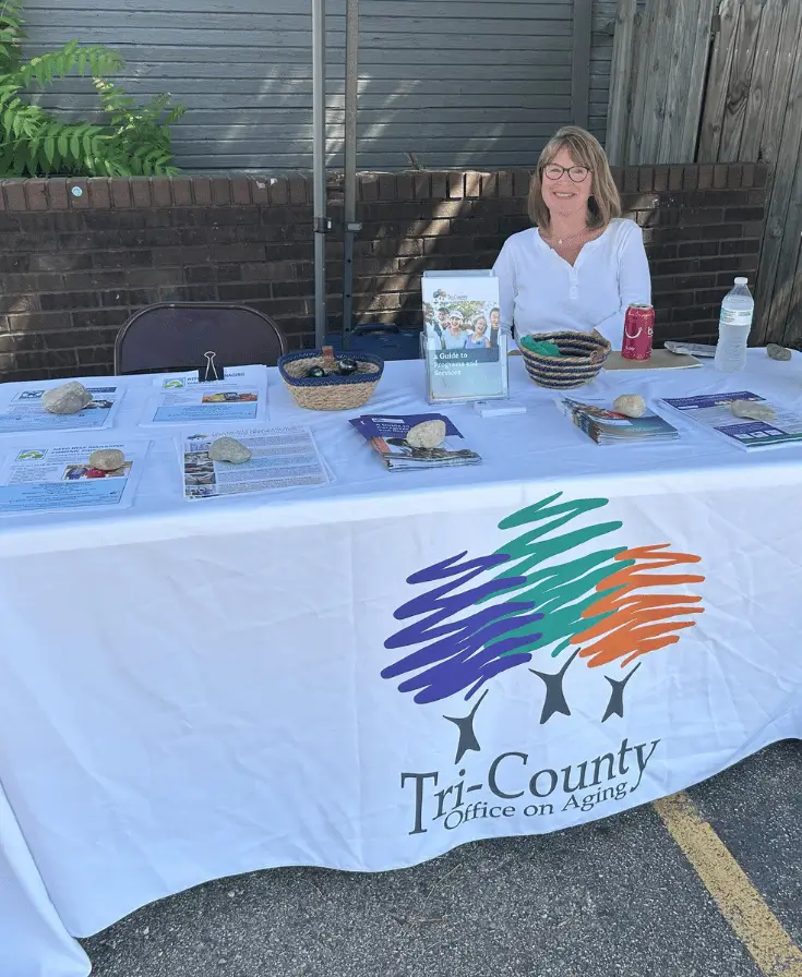 Person seated at a table with a banner in front